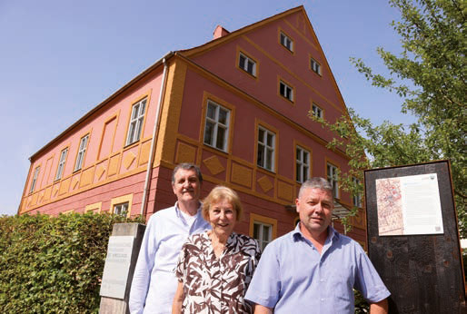 Die erste Infotafel (r.) stellte der gemeindliche Bauhof am alten Pfarrhof (im Hintergrund) in der Pfarrstraße 4 auf. Unser Bild zeigt (v. l.): Hans Schindlböck, Hiltrud Frühauf und Bürgermeister Peter Felbermeier. Foto: rds